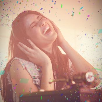 Pretty female DJ having fun while listening music on headphone against flying colours