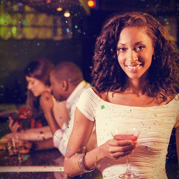 Portrait of young woman having cocktail at bar counter against flying colours