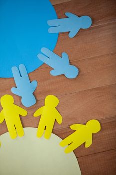 Conceptual image of blue and yellow paper cut-out people on the circle