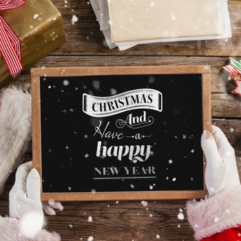 Santa claus holding a slate with merry christmas text against  logo wishing a merry christmas