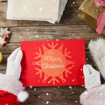 Santa claus holding a red placard against snowflake "merry christmas"