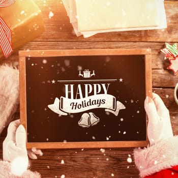 Santa claus holding a slate with merry christmas text against christmas message