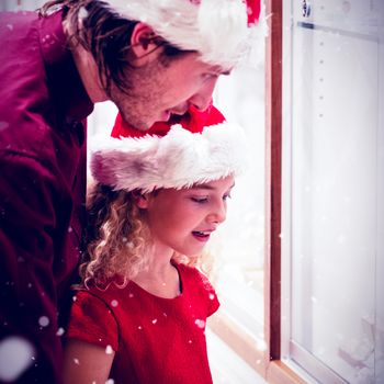 Side view of father and daughter in Christmas attire looking at jewelry display against snow falling