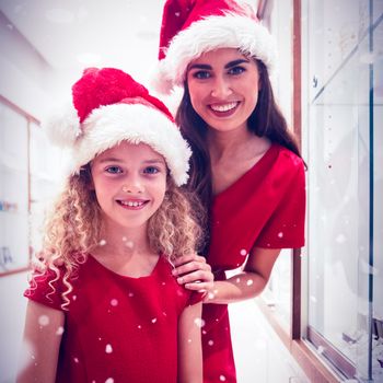 Portrait of mother and daughter in Christmas attire standing in jewelry shop against snow falling