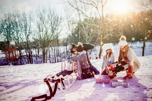 Family playing with sled against snow falling