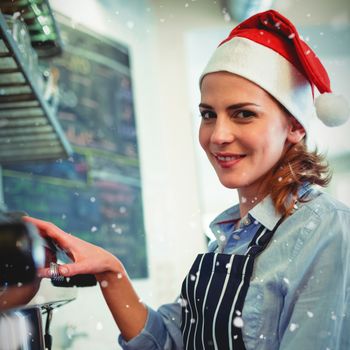 Portrait of waitress using coffee maker at cafeteria during Christmas against snow falling