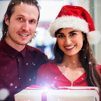 Portrait of couple in Christmas attire standing against snow falling