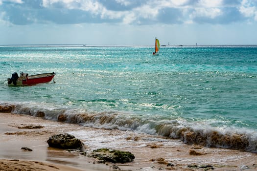 Sea view with waves running ashore and with boats and sailboats on the horizon