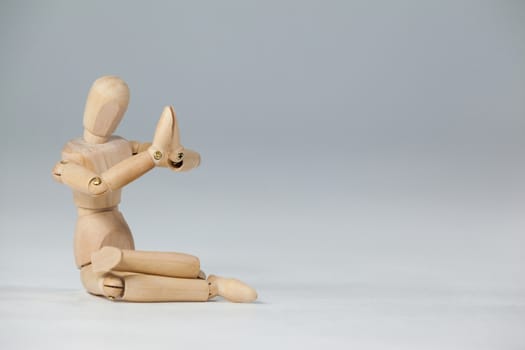 Wooden figurine performing yoga on floor against white background