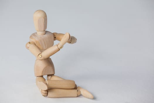 Wooden figurine performing yoga on floor against white background