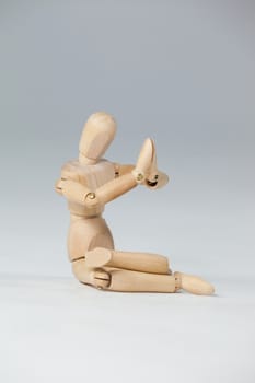 Wooden figurine performing yoga on floor against white background