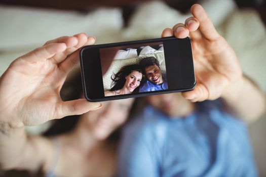 Romantic couple relaxing on bed and taking a selfie in bedroom