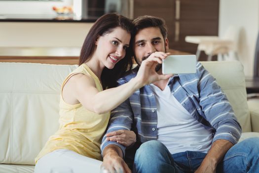 Romantic couple relaxing on sofa and taking a selfie in living room