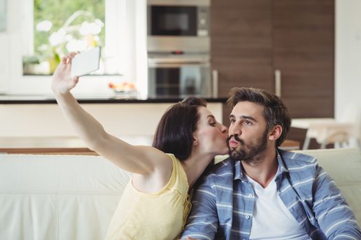 Romantic couple relaxing on sofa and taking a selfie in living room