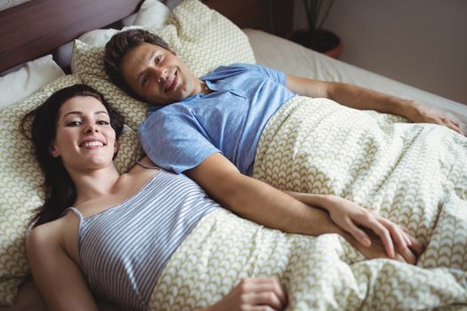 Portrait of romantic couple relaxing on bed in bedroom