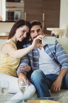 Romantic couple relaxing on sofa and taking a selfie in living room