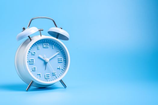 Blue color old fashioned bell alarm clock isolated on blue background