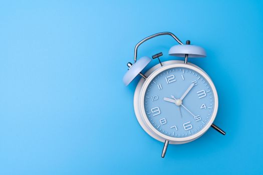 Blue color old fashioned bell alarm clock isolated on blue background