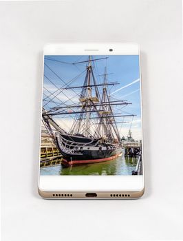 Modern smartphone with USS Constitution frigate docked in the Boston Harbor, USA. Concept for travel smartphone photography. All images in the composition are made by me and  available on my portfolio