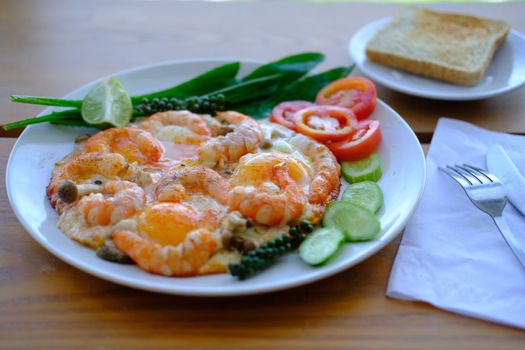 Close up of Fried eggs with prawns decorate fresh vegetables and toast, asian style food background 