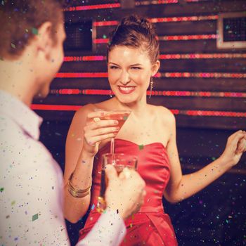 Smiling couple holding glass of beer and cocktail while dancing against flying colours