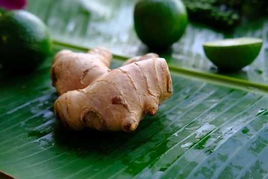 Ginger and lime whole and half on green banana leaf. Natural Raw vegetarian background.