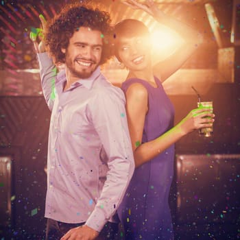 Cute couple dancing together on dance floor while having drink against flying colours