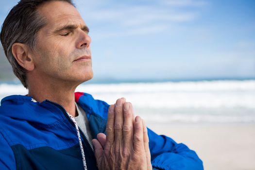 Mature man performing yoga on beach