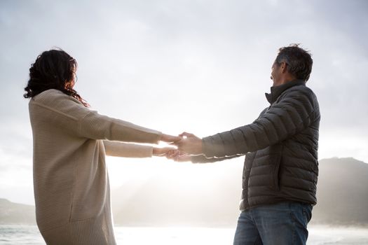 Romantic couple holding hands on beach during winter