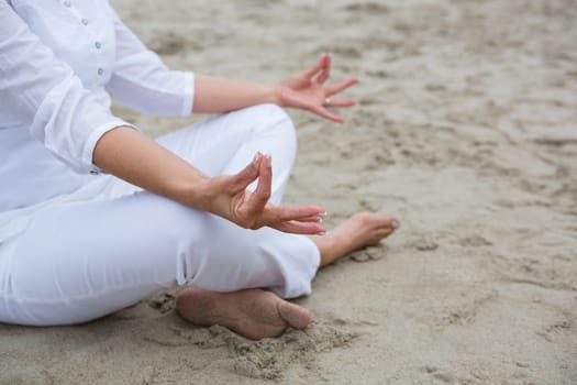 Mid section of woman performing yoga on beach