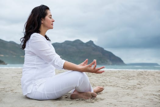 Beautiful woman performing yoga on beach