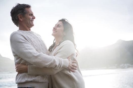 Romantic couple embracing each other on beach during winter