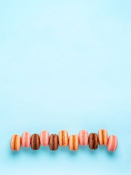 Macarons with copy space. Row of perfect french macarons or macaroons on blue background. Top view or flat lay