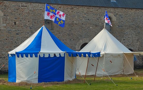 Medieval blue and white tents with normandy flag at top and castle in background