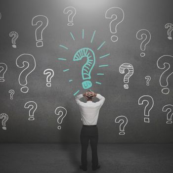 Anxious businessman looking at a drawing of question marks
