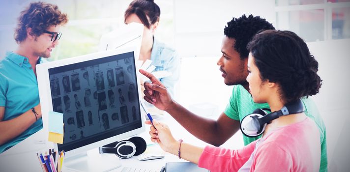 Group of casual young men and women working on computers in a bright office