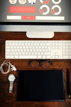 Business people with statistics on website against office desk with computer and digital tablet