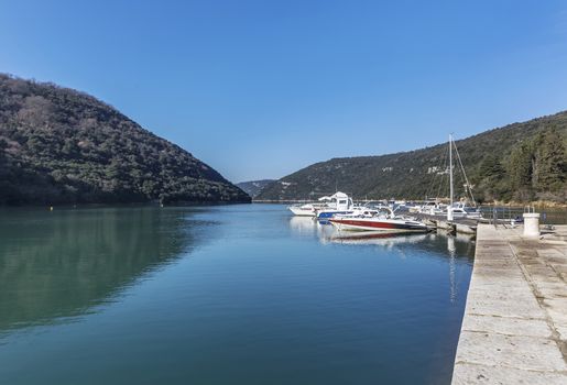 LIMSKI KANAL, CROATIA - January 29, 2020: Anchored boats in a sunny port in the Lim Canal, Istria, Croatia