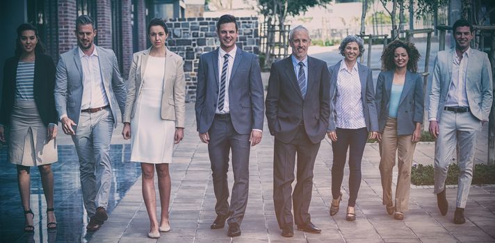 Portrait of smiling business people walking outside office building