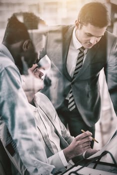 Business people discussing over document seen through glass in office