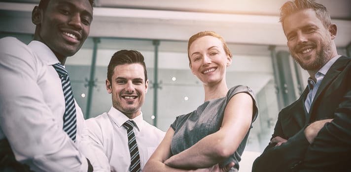 Portrait of happy business people standing with arms crossed in office