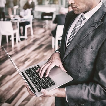Focused businessman using laptop while standing in office