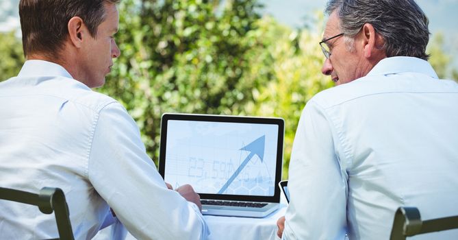 Business people discussing over laptop while sitting outdoors