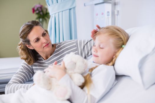 Mother comforting her daughter in hospital bed