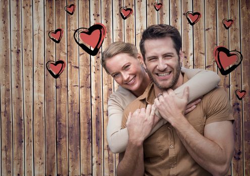 Portrait of romantic couple against wooden background with heart shapes
