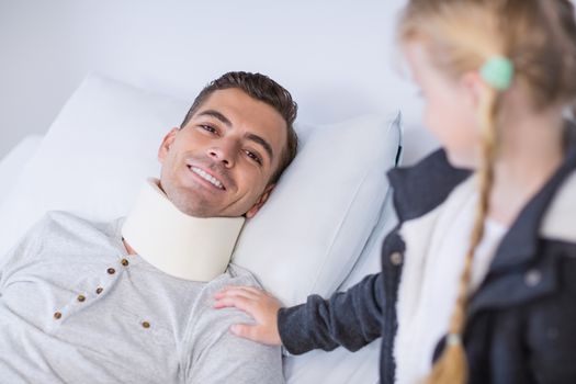 Smiling daughter comforting her sick father in hospital room