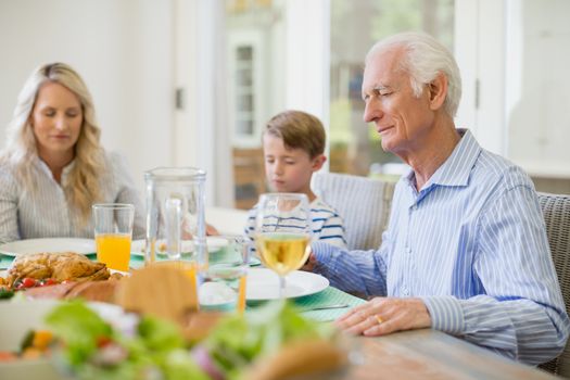 Multi-generation family praying before having meal at home