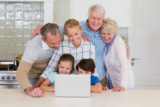 Happy family using laptop in kitchen at home