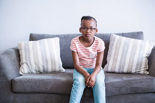 Upset girl sitting on sofa in corridor at hospital