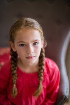 Portrait of cute girl sitting on chair at home